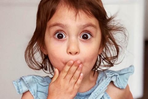 Girl covering her mouth with her hand and a look of surprise on her face