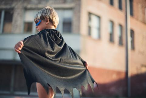 Boy with a cape posing as a super hero