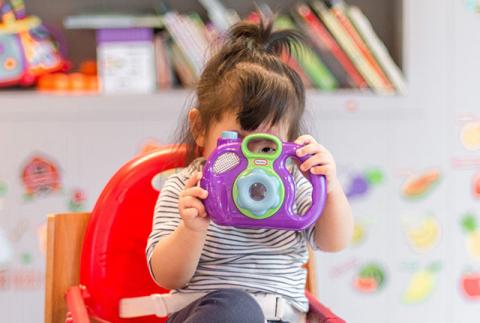 Child looking through the viewfinder on a toy camera