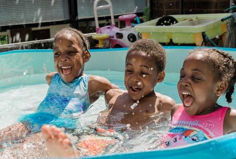 Three children laughing in a paddling pool